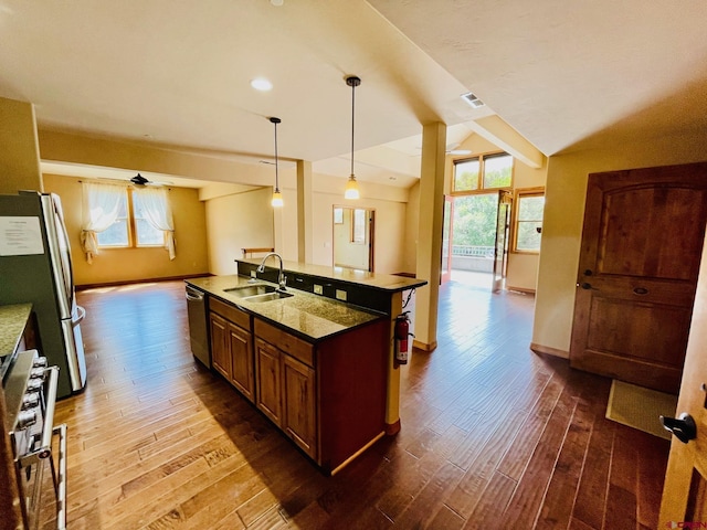 kitchen with decorative light fixtures, a healthy amount of sunlight, stainless steel appliances, and an island with sink