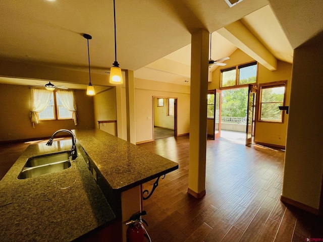 kitchen featuring ceiling fan, sink, decorative light fixtures, vaulted ceiling with beams, and a breakfast bar area