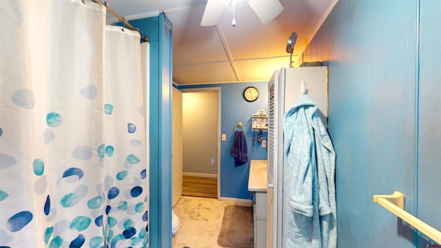 bathroom featuring ceiling fan, a shower with curtain, toilet, wooden walls, and vanity