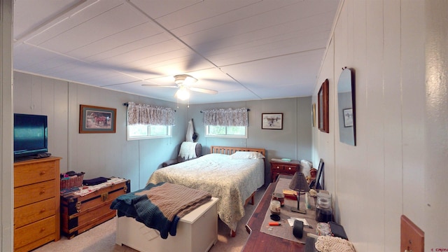 bedroom featuring ceiling fan and wooden walls