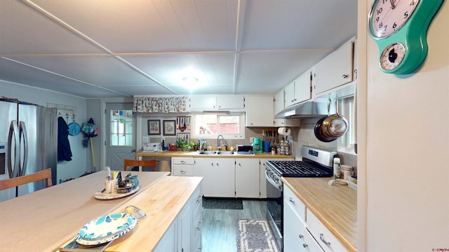 kitchen with wood counters, stainless steel appliances, sink, dark hardwood / wood-style floors, and white cabinetry