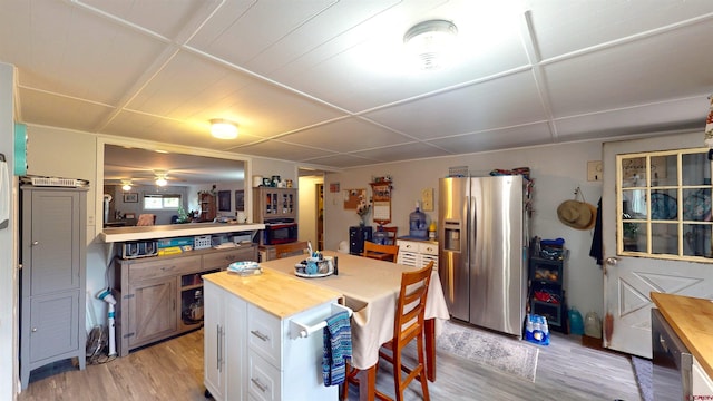 kitchen with stainless steel refrigerator with ice dispenser, light wood-type flooring, white cabinetry, and ceiling fan