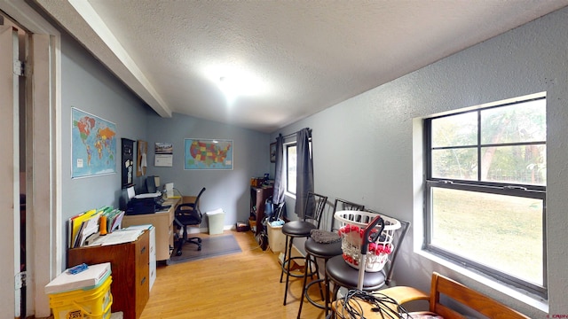 office space featuring light wood-type flooring, a textured ceiling, and vaulted ceiling