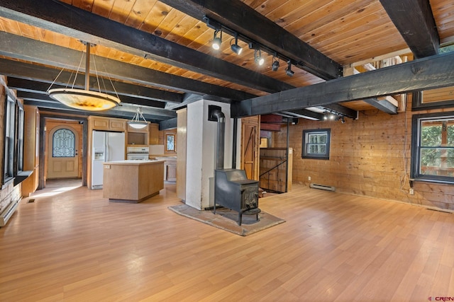 interior space with wooden ceiling, light hardwood / wood-style floors, a wood stove, white fridge with ice dispenser, and wood walls