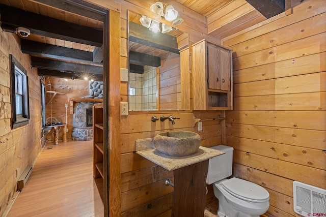 bathroom with vanity, wood walls, hardwood / wood-style flooring, toilet, and beamed ceiling