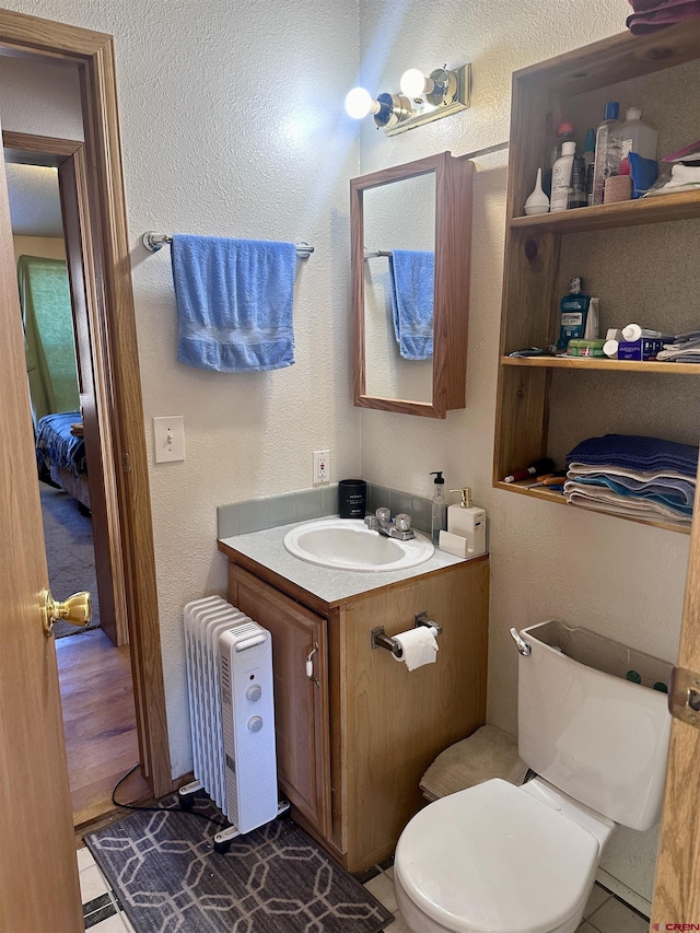 bathroom with hardwood / wood-style floors, vanity, toilet, and radiator heating unit