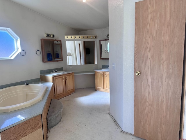 bathroom with concrete flooring, vanity, vaulted ceiling, and a tub