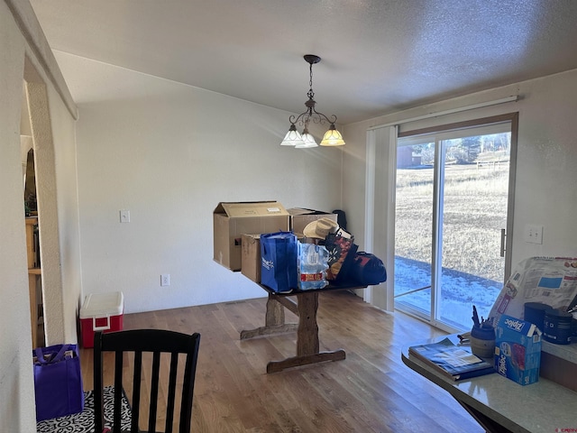 dining room with a notable chandelier, a textured ceiling, and light hardwood / wood-style flooring