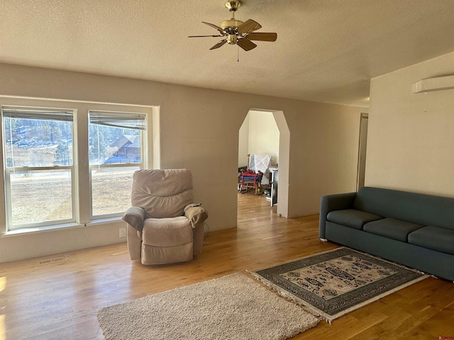 living room with ceiling fan, wood-type flooring, and a textured ceiling