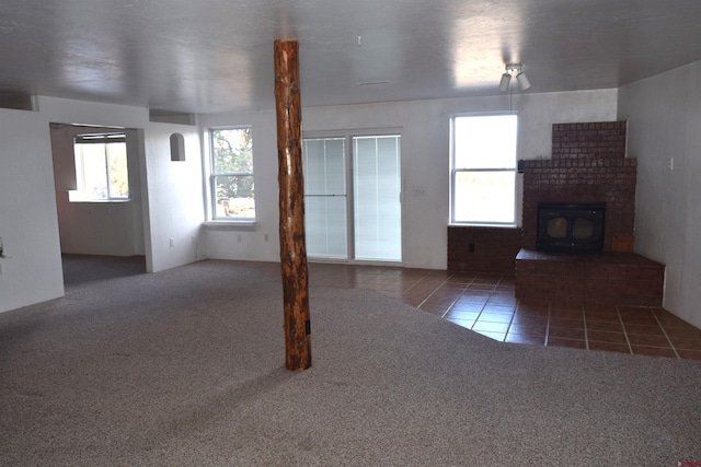 unfurnished living room featuring dark tile patterned flooring and a brick fireplace