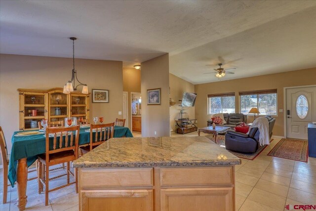 kitchen with ceiling fan with notable chandelier, a textured ceiling, light tile patterned floors, light brown cabinets, and hanging light fixtures