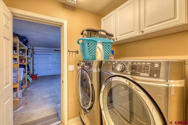 clothes washing area featuring washer and clothes dryer, cabinets, and a textured ceiling