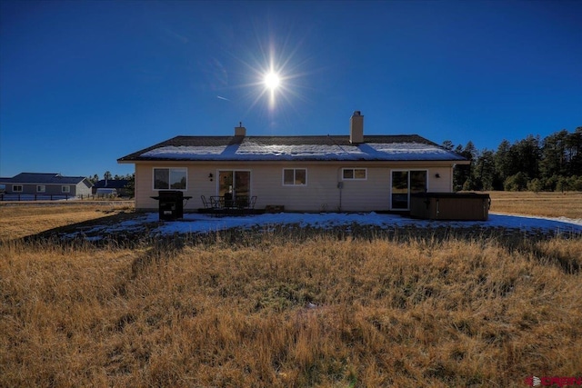 rear view of property featuring a hot tub