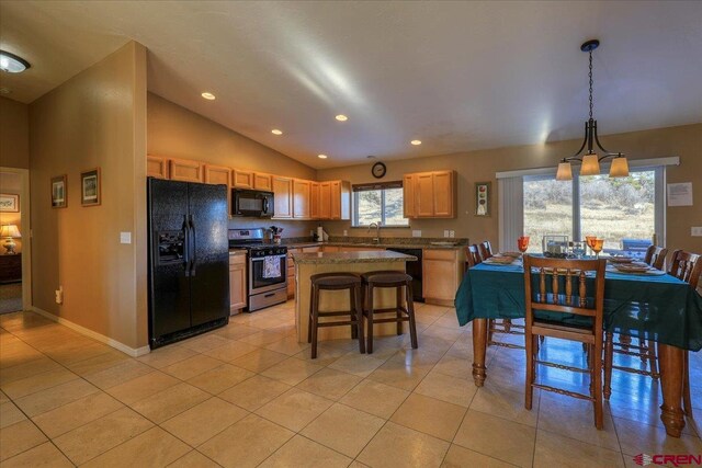 kitchen featuring black appliances, a healthy amount of sunlight, a kitchen island, and hanging light fixtures