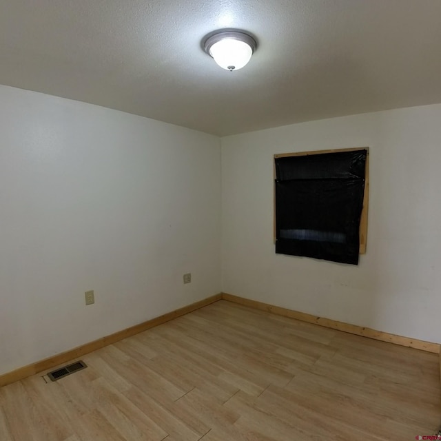 unfurnished room featuring a textured ceiling and light hardwood / wood-style flooring