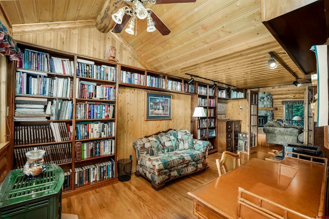 sitting room with wooden ceiling, lofted ceiling with beams, a stone fireplace, ceiling fan, and light wood-type flooring