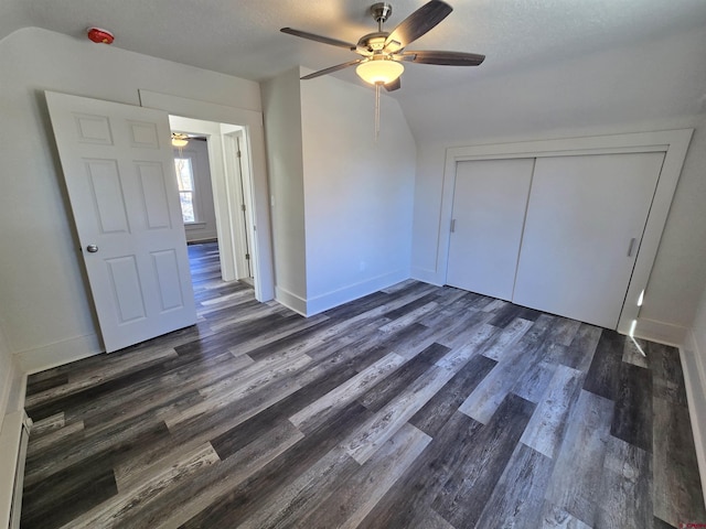 unfurnished bedroom featuring ceiling fan, dark hardwood / wood-style floors, lofted ceiling, a textured ceiling, and a closet