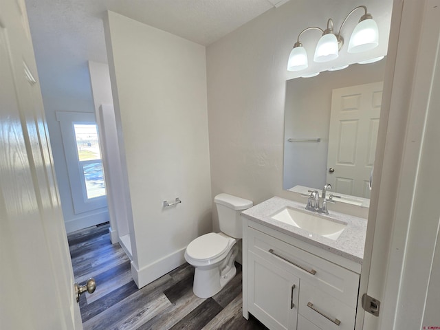 bathroom featuring hardwood / wood-style flooring, vanity, toilet, and a textured ceiling