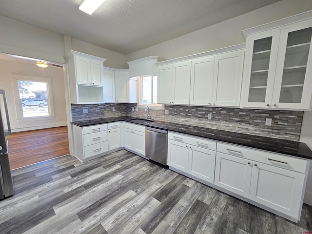 kitchen featuring hardwood / wood-style floors, white cabinets, sink, stainless steel dishwasher, and tasteful backsplash