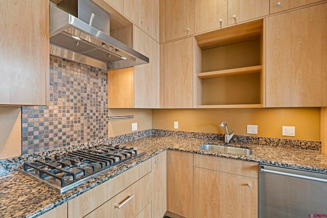 kitchen with wall chimney exhaust hood, sink, stainless steel appliances, and dark stone counters