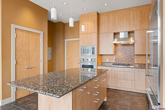 kitchen featuring a center island, dark tile patterned flooring, wall chimney exhaust hood, dark stone countertops, and appliances with stainless steel finishes