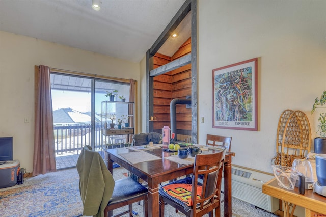 carpeted dining area featuring a textured ceiling, a wood stove, and lofted ceiling