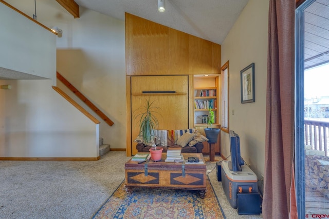 living area featuring carpet floors, wooden walls, high vaulted ceiling, and beam ceiling