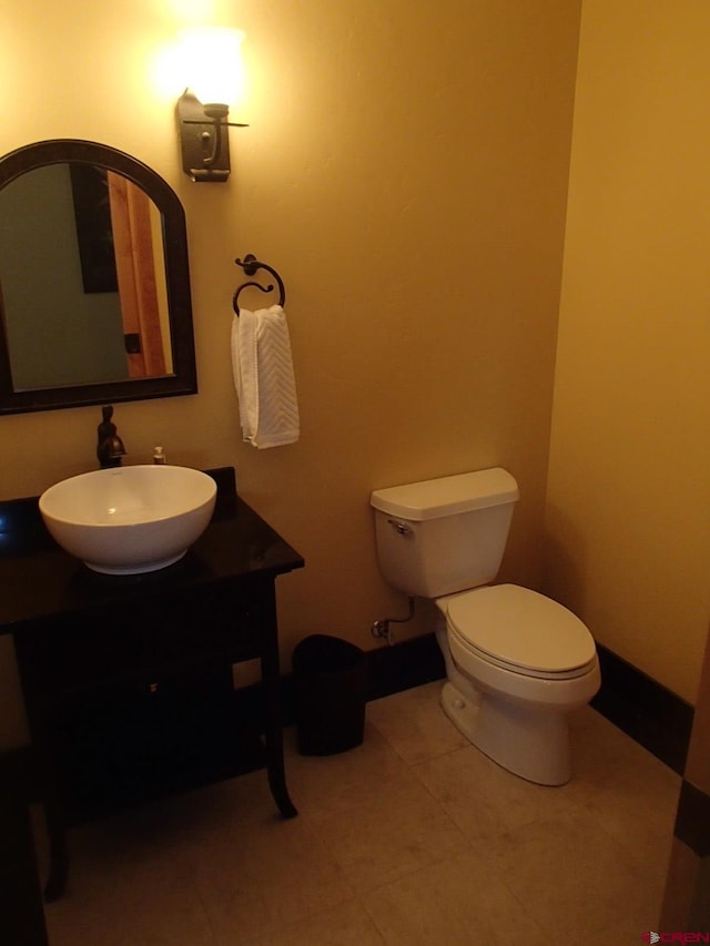 half bathroom featuring baseboards, vanity, toilet, and tile patterned floors