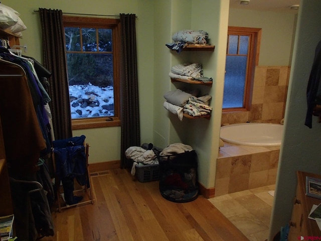 interior space featuring baseboards, a bath, and wood finished floors