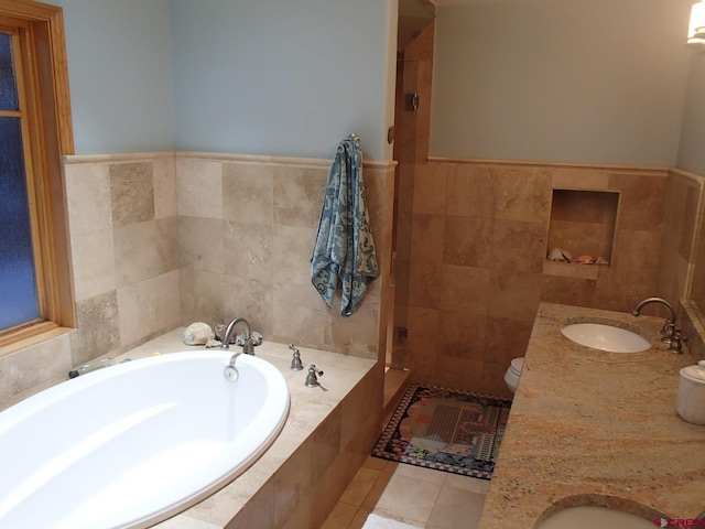 bathroom featuring toilet, a sink, a bath, tile patterned floors, and double vanity