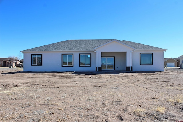 view of front of house featuring roof with shingles and stucco siding