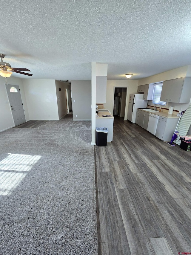 unfurnished living room featuring a textured ceiling, hardwood / wood-style flooring, ceiling fan, and sink