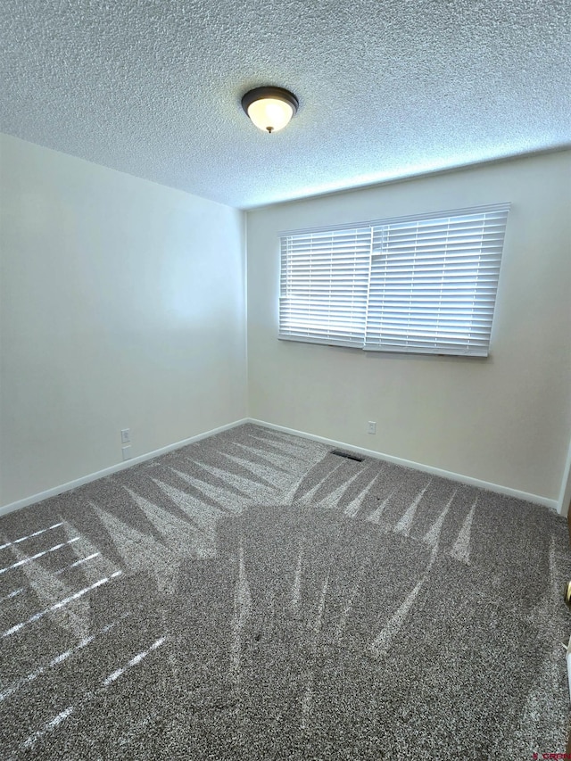 carpeted spare room featuring a textured ceiling