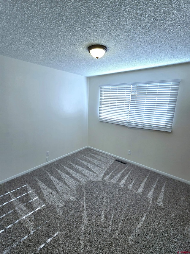 carpeted empty room featuring a textured ceiling