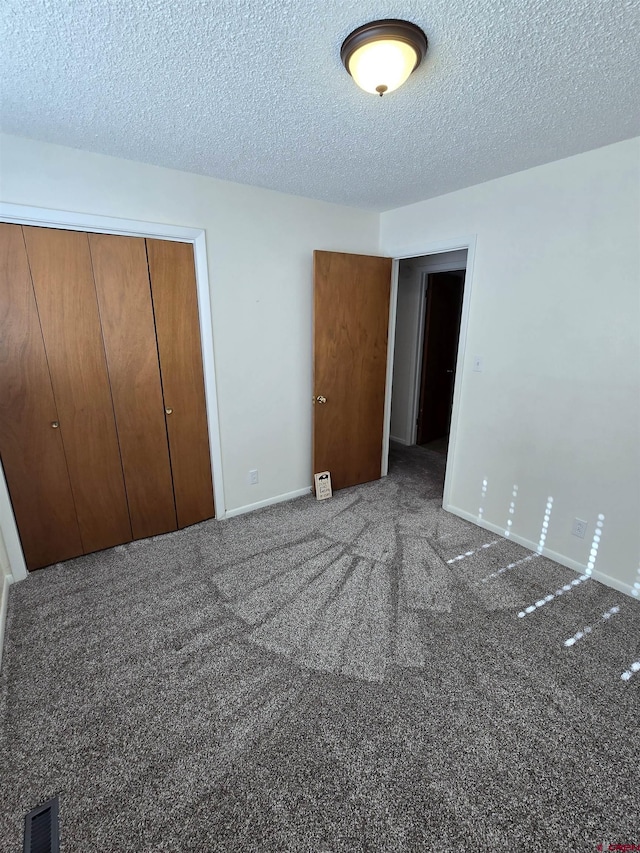 unfurnished bedroom featuring a textured ceiling, carpet floors, and a closet