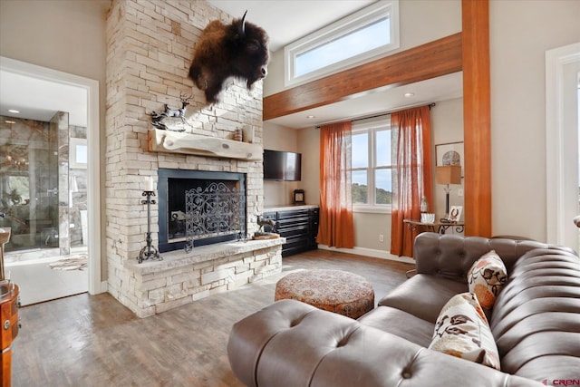 living room featuring a stone fireplace, dark hardwood / wood-style flooring, and a high ceiling