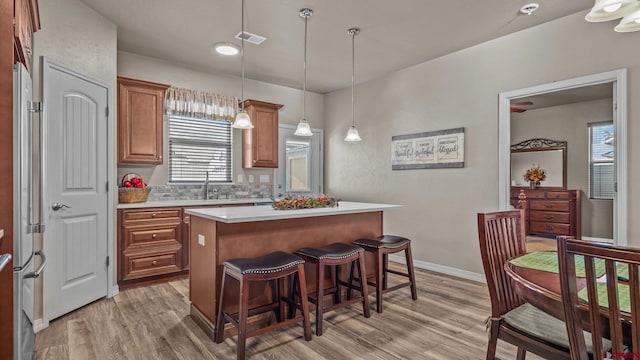 kitchen with tasteful backsplash, a kitchen island, hanging light fixtures, and light hardwood / wood-style floors