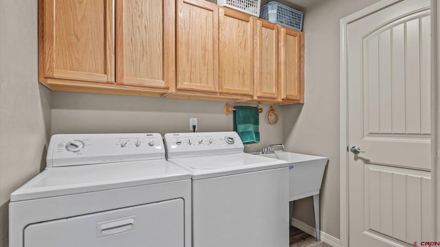 clothes washing area featuring cabinets, wood-type flooring, and separate washer and dryer