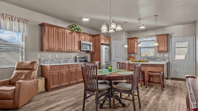 kitchen featuring pendant lighting, an inviting chandelier, stainless steel appliances, and light hardwood / wood-style floors