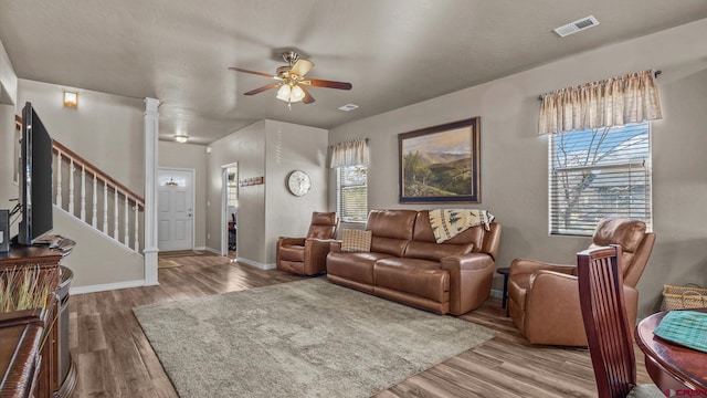 living room featuring decorative columns, ceiling fan, and wood-type flooring