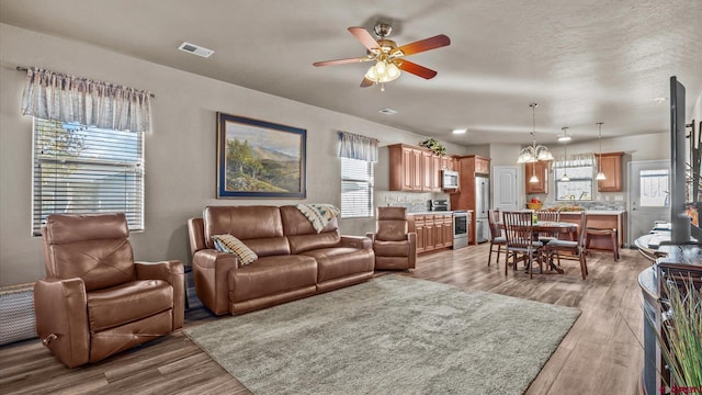 living room with ceiling fan, a healthy amount of sunlight, and light hardwood / wood-style flooring