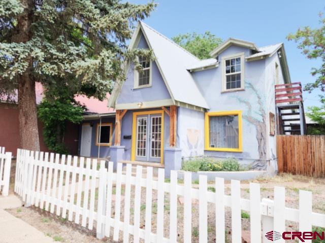 318 E Main St, Cortez, CO 81321 - view of front of home featuring stucco siding and a fenced front yard