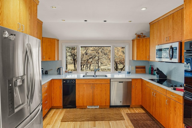 kitchen with decorative backsplash, sink, black appliances, and light hardwood / wood-style floors