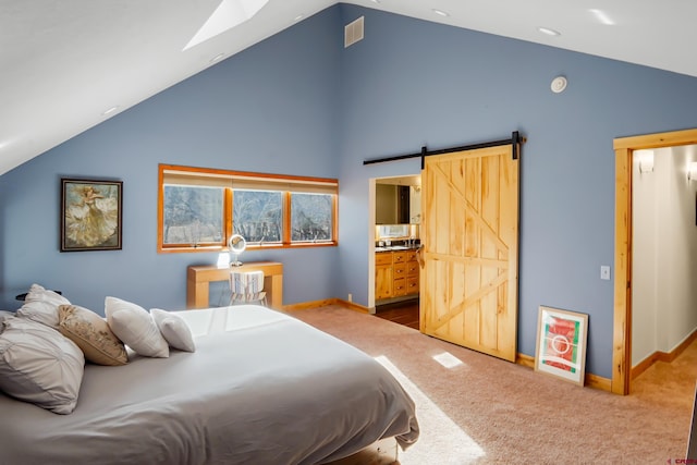 bedroom with lofted ceiling with skylight, a barn door, carpet floors, and ensuite bath