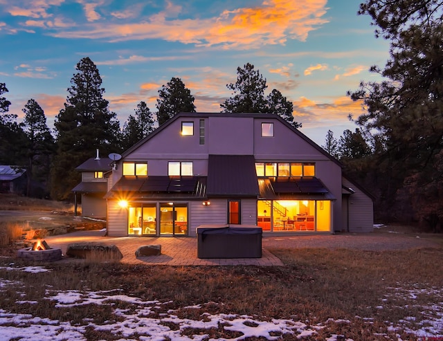 snow covered property with a patio area, an outdoor fire pit, and a hot tub