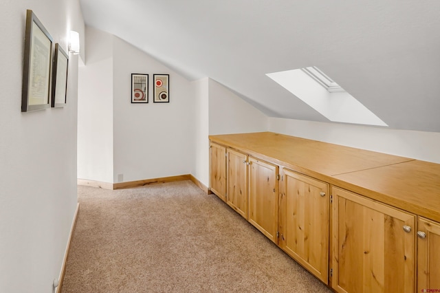 additional living space featuring light carpet and vaulted ceiling with skylight