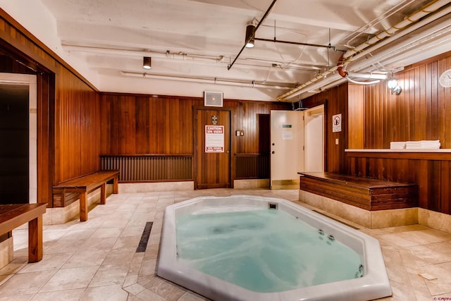 miscellaneous room featuring a jacuzzi, light tile patterned floors, and wood walls