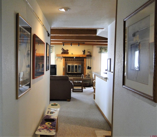 corridor with beamed ceiling, a barn door, carpet floors, and a textured ceiling