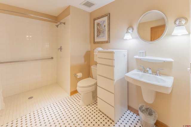 bathroom featuring a tile shower, tile patterned flooring, and toilet