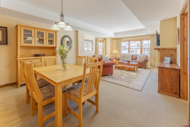 dining room featuring light carpet and a raised ceiling